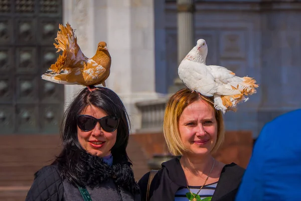 Moskou, Rusland - April, 24, 2018: Unidentified twee jonge vrouwen staat op een straat met een duif in haar hoofd, mooi meisje — Stockfoto