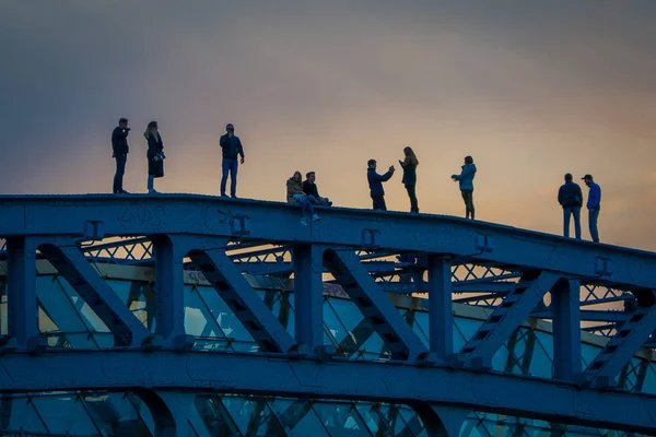 MOSCOW, RÚSSIA- ABRIL, 24, 2018: Adolescentes tirando fotos e caminhando sobre a ponte Andreevsky, o dique do rio Moscou, centro da cidade lugar popular para caminhar em vista lindo pôr do sol — Fotografia de Stock