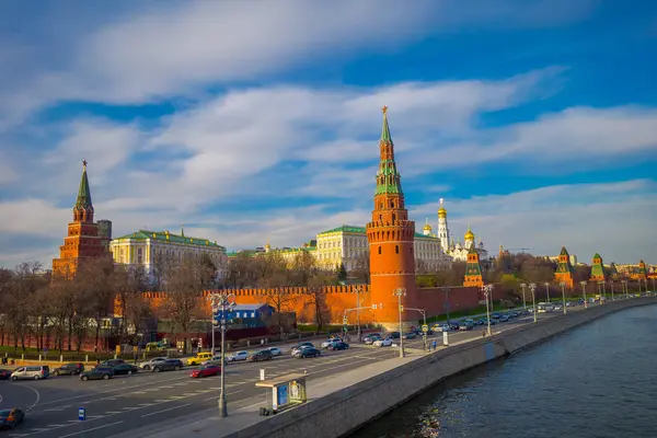 Moskau, russland - 24. april 2018: aussenansicht des spasskaya turms an einer flussseite mit einigem verkehr an einem sonnigen tag mit kremlin wall — Stockfoto