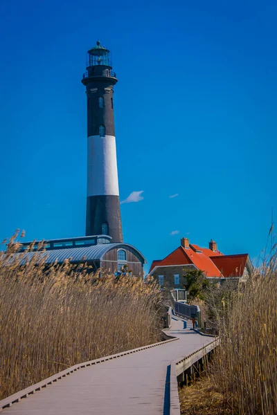 LONG ISLAND, USA, APRIL, 04, 2018: Outdoor view of long wooden bridge in a beautiful sunny day with blue sky with Montauk Lighthouse behind, at Long island — Stock Photo, Image