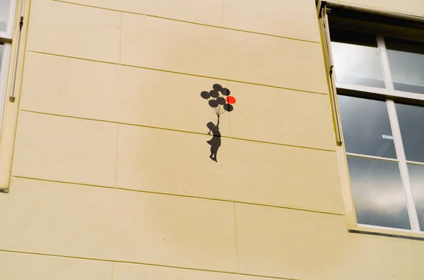 AMSTERDÃO, PAÍSES BAIXOS, 23 de abril de 2018: Vista ao ar livre da figura da menina com balões nas mãos sobre a parede de um edifício da rua no dowtown — Fotografia de Stock