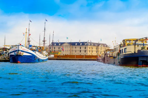 Amsterdam, Niederlande, 23. April 2018: Außenansicht vieler Boote am Ufer von Kanälen, ist die Hauptstadt und bevölkerungsreichste Stadt der Niederlande mit einem Gebäude-Infrastruktur hinter — Stockfoto