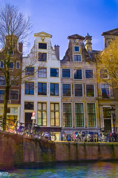 Amsterdam, Nederland, April, 23 2018: Outdoor weergave van sommige fietsen geparkeerd in een rij in een riverside van het kanaal van Amsterdam, is de hoofdstad en grootste stad van Nederland — Stockfoto