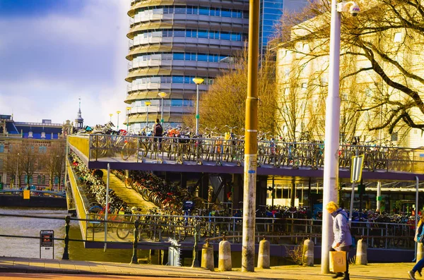 Amsterdam, Nederländerna, April, 23 2018: Utomhus syn på några cyklar parkerade i rad i en riverside av kanalen i Amsterdam, är huvudstaden och den mest folkrika staden i Nederländerna — Stockfoto