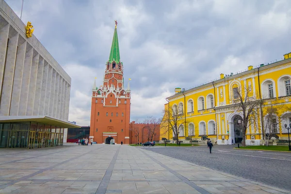 MOSCÚ, RUSIA - 24 DE ABRIL DE 2018: Vista al aire libre de personas no identificadas caminando en una plaza con una torre Spasskaya detrás en las calles, durante un día soleado con el muro del Kremlin —  Fotos de Stock