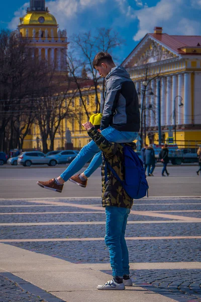 ST. PETERSBURG, RUSIA, 02 MAYO 2018: Hombre no identificado sobre los hombros de su amigo o novio haciendo acrobacias con el edificio del Almirantazgo detrás, durante un día soleado en San Petersburgo —  Fotos de Stock