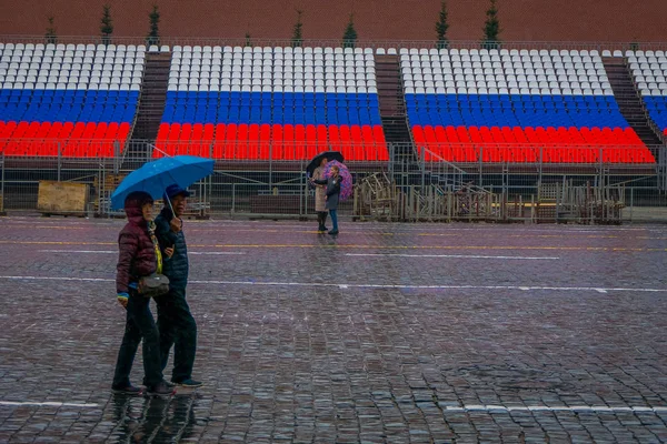 MOSCOU, RUSSIE - 29 AVRIL 2018 : Vue extérieure de personnes non identifiées portant des vêtements chauds et des parapluies, se protégeant de la pluie et marchant sur la place rouge et le monument de l'architecture à Moscou — Photo