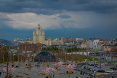 MOSCOW, RUSSIA- APRIL, 24, 2018: Above view of arbat street with unidentified tourists walking close to pink trees in the boulevar and International Business Center behind in Moscow clipart