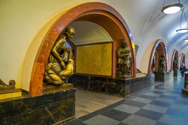 MOSCÚ, RUSIA - 29 DE ABRIL DE 2018: Turista caminando en una estación de metro en Ploshchad Revolyutsii, con una hermosa escultura de bronce en la esquina del arco dentro del edificio en Moscú —  Fotos de Stock