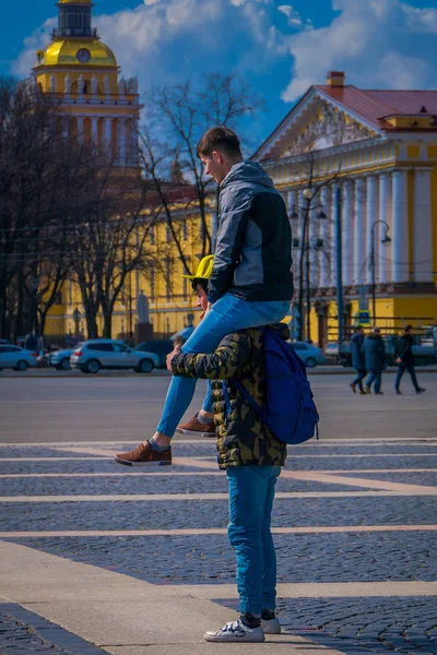 ST. PETERSBURG, RUSIA, 02 MAYO 2018: Hombre no identificado sobre los hombros de su amigo o novio haciendo acrobacias con el edificio del Almirantazgo detrás, durante un día soleado en San Petersburgo —  Fotos de Stock