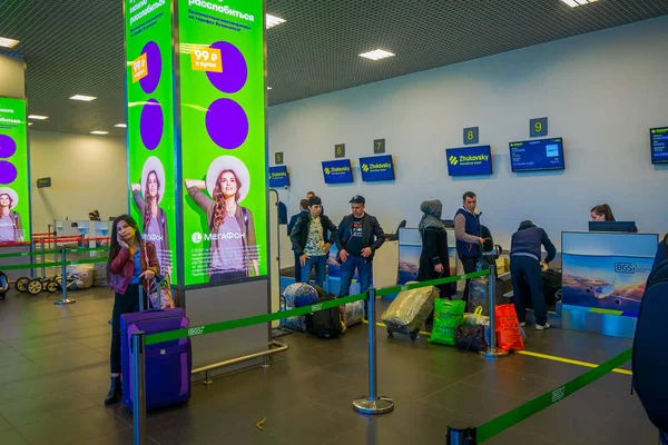 白俄罗斯明斯克-2018年5月01日: 在办理登机手续的情况下, 在明斯克机场内的不明身份人员的室内视野在不同国家五颜六色的标志和游客周围 — 图库照片
