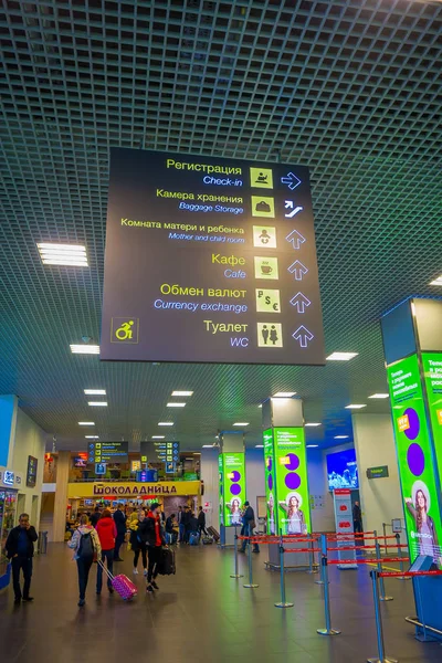 MINSK, BELARUS - 01 MAI 2018 : Vue intérieure de touristes non identifiés marchant avec leurs bagages sous un panneau informatif près de la zone d'enregistrement à l'intérieur de l'aéroport de Minsk — Photo
