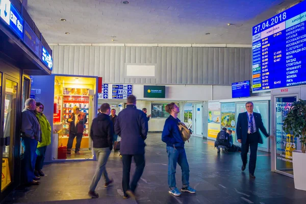 MINSK, BELARUS - 01 DE MAYO DE 2018: Personas no identificadas caminando con sus maletas y viendo una pantalla de salida, ubicada dentro del aeropuerto de Minsk — Foto de Stock