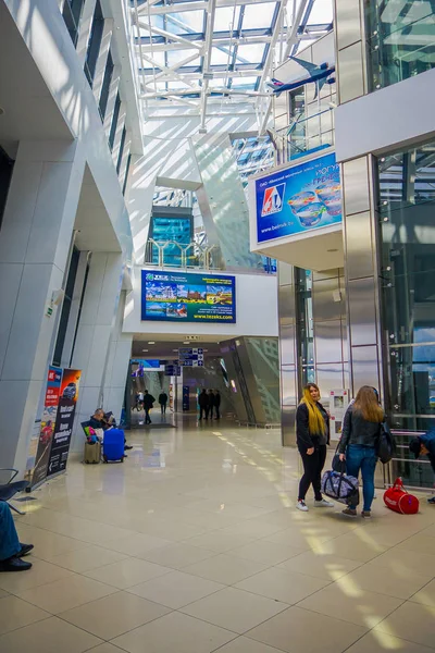 Minsk, Weißrussland - 01. Mai 2018: Reisende in einem Warteraum im Inneren des internationalen Flughafens von Minsk mit einem Bildschirm für Abflüge und Ankünfte für ihren Flug — Stockfoto
