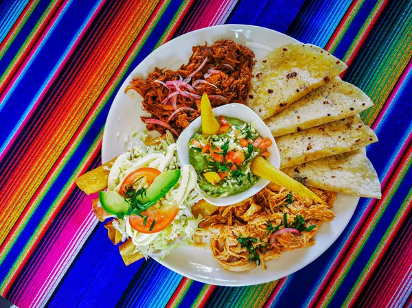メキシコ料理は、カラフルな背景、グアカモーレ、コチニータ・ピビル、フラウタス、ケサディラをミックスします。. — ストック写真