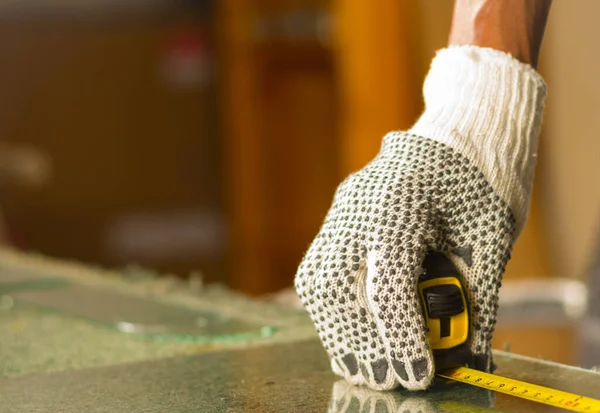 Main étroite portant des gants de travail blancs à l'aide d'un outil de mesure sur un morceau de verre transparent — Photo