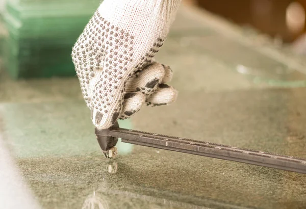 Κοντινό χέρι φορώντας λευκά γάντια εργασίας χρησιμοποιώντας εργαλείο κοπής μετάλλων σε διαφανές κομμάτι γυαλιού — Φωτογραφία Αρχείου
