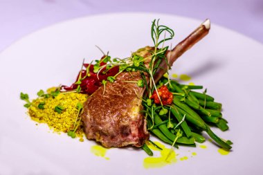 Beyaz seramik tabak haşlanmış yeşil fasulye, pancar suyu ile renkli soğan ile servis bir Kuzu pirzola ile sarı taşımak fıstık, biberiye ve fasulye filizi ile dekore edilmiştir. Yan görünüm