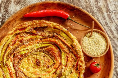 Ev yapımı yuvarlak sebze pasta ahşap masa üzerinde taze kiraz domates, biber ve susam bir ahşap tepsi tahta kaşıkla ahşap bir tencerede ile devam eder. Üstten Görünüm. 