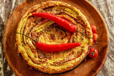 Ev yapımı yuvarlak sebze pasta taze kiraz domates ile servis ve iki pul biber ile dekore edilmiş ve ahşap masa üzerinde bir ahşap tepsi susam serpilir. Üstten Görünüm. 