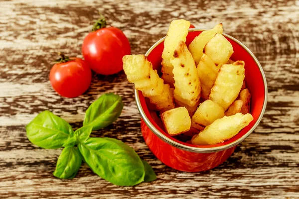 Ahşap masa üzerinde iki kiraz domates ile dekore edilmiş patates kızartması ile kırmızı emaye Kupası. Üstten Görünüm.   
