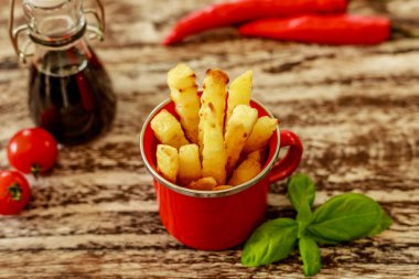 Patates kızartması ile kırmızı emaye fincan fesleğen yaprağı, kiraz domates ve kırmızı biber soğuk, ahşap masa üzerinde dekore edilmiş cam sos tencerede balzamik sos ile servis. Üstten Görünüm.