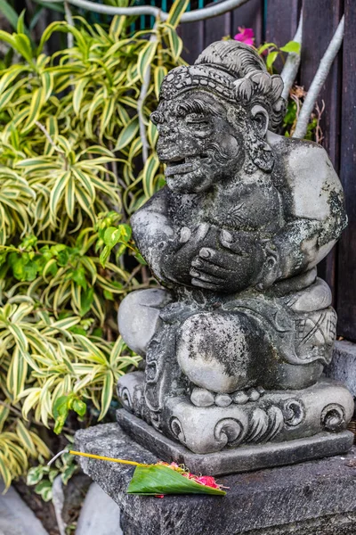 Estatua de guardia cerca de la casa balinesa con ofrenda de sari canang, isla de Bali, Indonesia — Foto de Stock