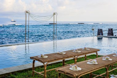 Düğün töreni Kur günbatımı - rattan banklar çiçek yaprakları ve bambu fanlar ve bir düğün kemer ile misafirler için denize yakın