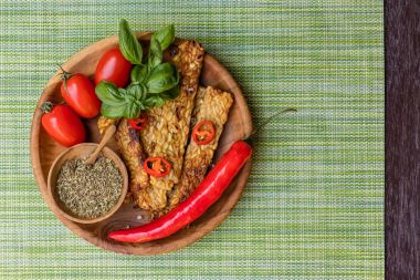 Kızarmış biber, taze domates ve yeşil peçete üzerinde yuvarlak bir ahşap tepsi tahta kaşıkla ahşap tencerede kuru baharat karışımı ile Tempe. Üstten Görünüm alanı ile