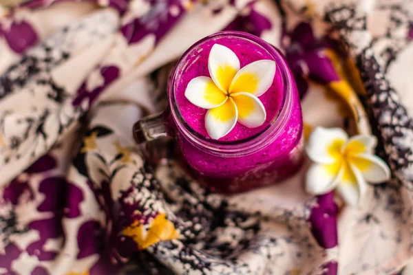 Red Dragon meyve suyu bir bardak çiçekli kumaş üzerinde Plumeria çiçek ile dekore edilmiştir. Üstten Görünüm. 