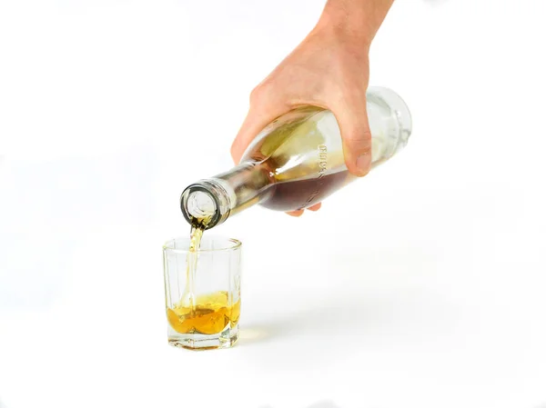 Ręka wlewa kieliszek koniaku z butelki — Zdjęcie stockowe