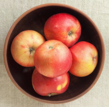 Bir kasede kahverengi bir arka plan üzerinde kırmızı elmalar