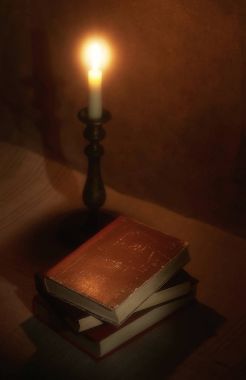 mum ışığında ahşap bir masa üzerine eski kitap