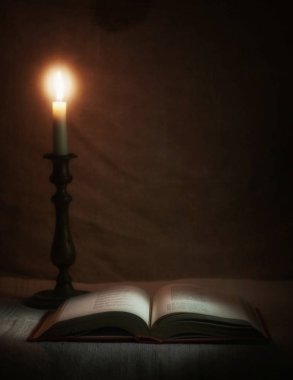 mum ışığında ahşap bir masa üzerine eski kitap