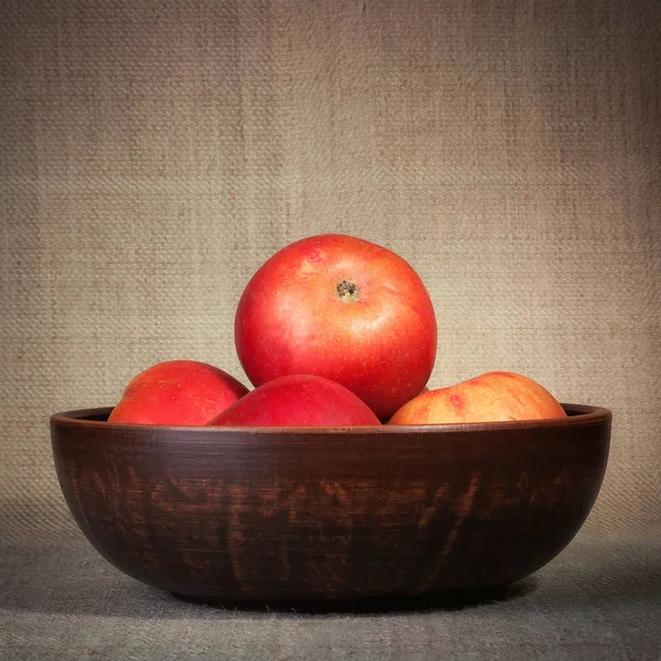 Красные яблоки на коричневом фоне в миске — стоковое фото