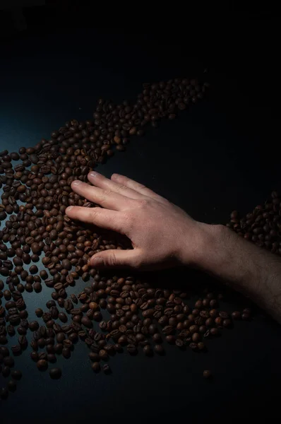 暗闇の中でコーヒー豆を持つ労働者の手 — ストック写真