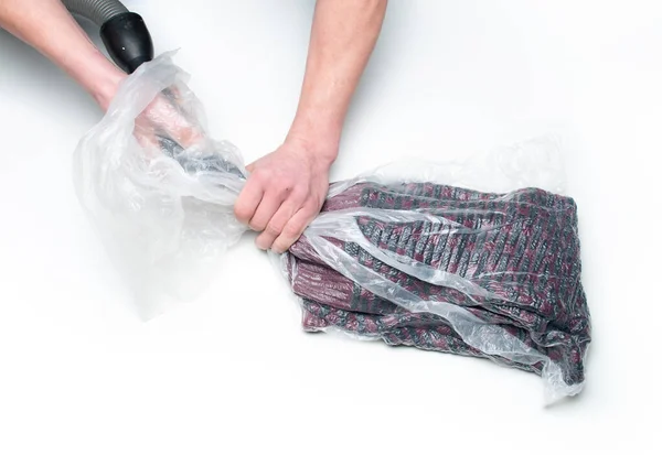 Ο άνθρωπος βάζει ρούχα σε μια σακούλα κενού. — Φωτογραφία Αρχείου