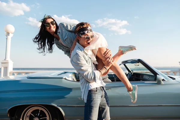 Hombre llevando a su mujer y divirtiéndose cerca de cabriolet vintage —  Fotos de Stock