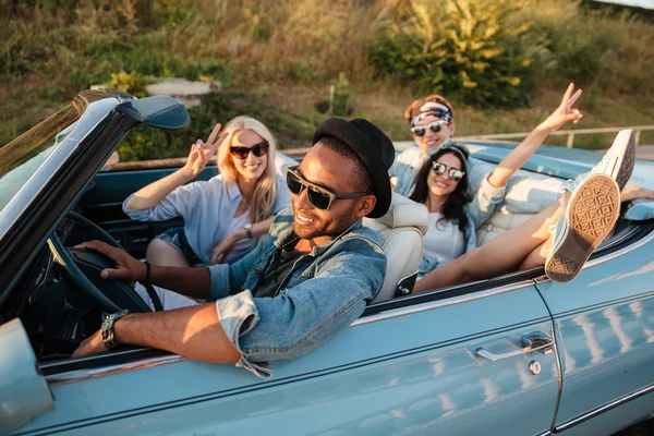 Lächelnde Freunde fahren Auto und zeigen Friedenszeichen im Sommer — Stockfoto