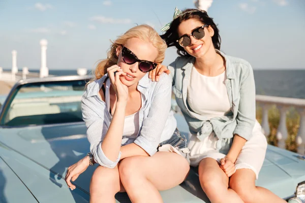Due donne sedute sul cofano dell'auto insieme — Foto Stock