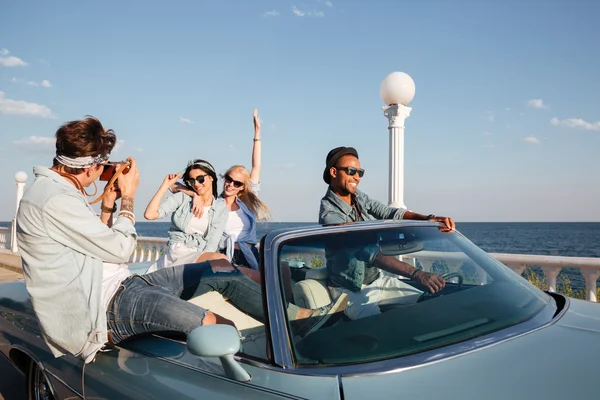 Cheerful young people driving a car and talking photos — Stock Photo, Image