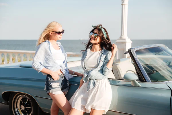Two women standing near cabriolet in summer