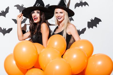 Turuncu balonlar ile cadı cadılar bayramı kostümleri iki mutlu kadın