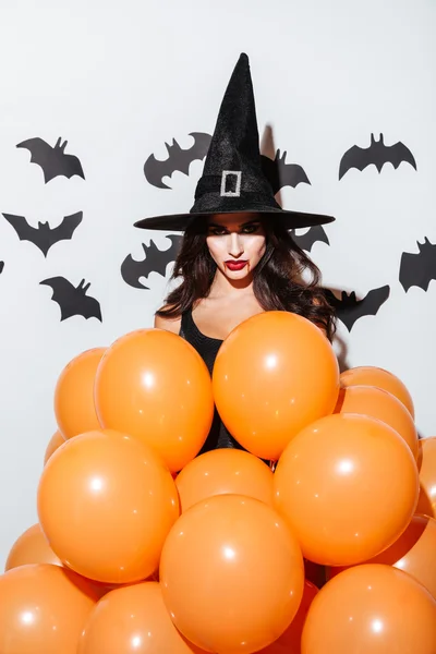 Atractiva joven con disfraz de bruja de Halloween con globos naranjas —  Fotos de Stock