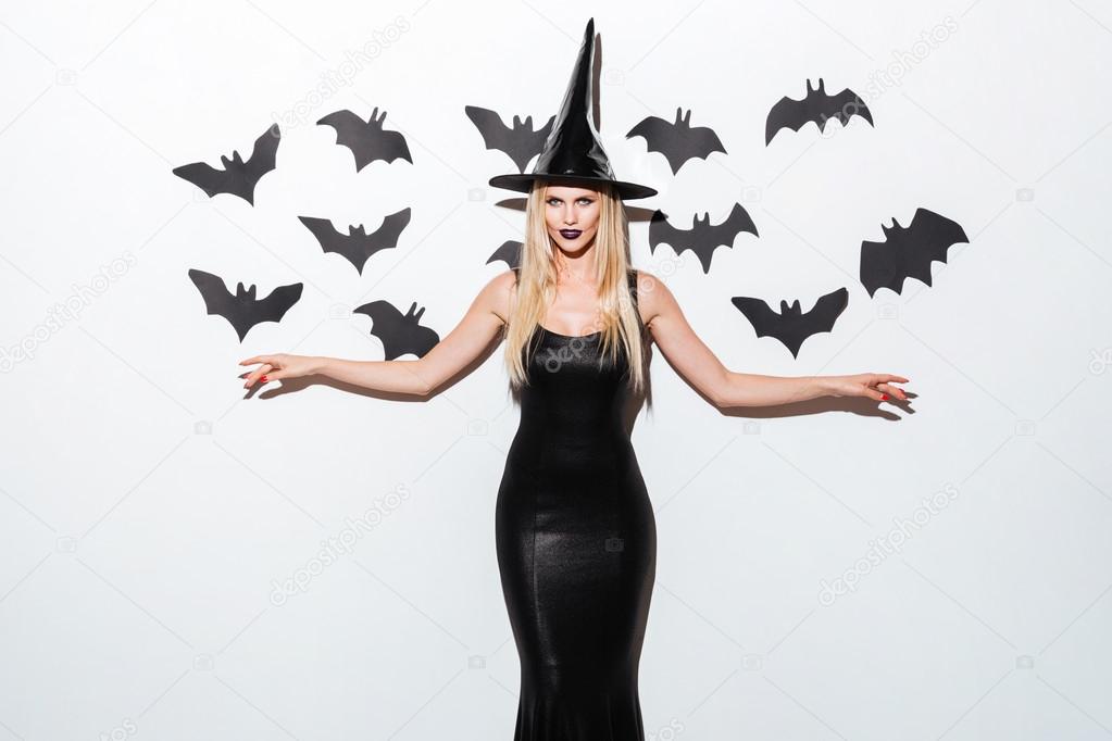 Happy young woman in black wich halloween costume with hat