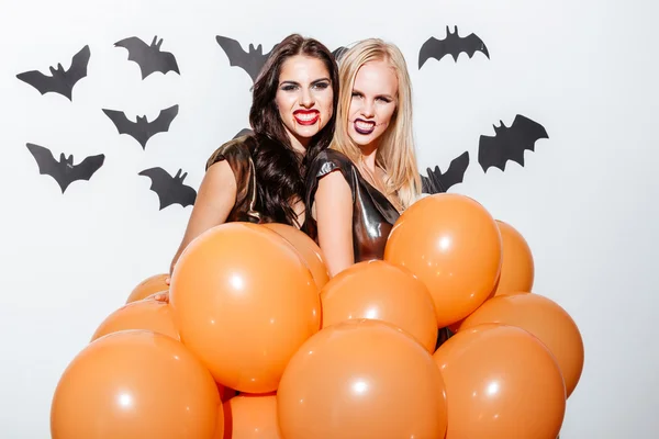 Mujeres aterradoras con maquillaje de Halloween sosteniendo globos y mostrando dientes —  Fotos de Stock