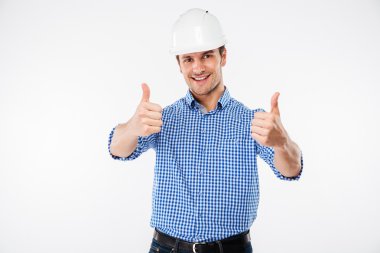 Başparmak gösterilmesini kask binada neşeli genç adam ölçmek