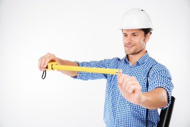 Mutlu genç adam binanın mühendisini ölçüm bandı kullanarak kask içinde