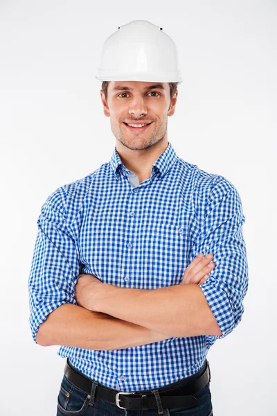 Щасливий чоловік будівельник у жорсткому капелюсі, що стоїть з схрещеними руками — стокове фото