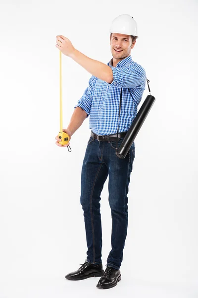 Baret ölçüm bandı kullanarak gülümseyen genç adam mimar — Stok fotoğraf